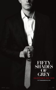 Poster for Fifty Shades of Grey featuring a black-and-white image of a man in a tailored suit, seen from the shoulders down. He grips a textured necktie suggestively in one hand. The tagline includes the release date “Valentine’s Day 2015,” reinforcing the romantic and erotic themes of the film. The overall tone is sleek, minimalist, and provocative.