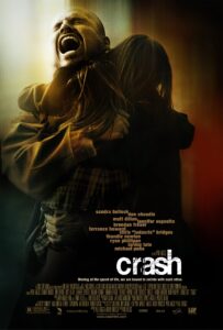 Poster for Crash featuring a dramatic close-up of a man (Michael Peña) mid-scream, holding a young girl tightly in a protective embrace. The image is blurred at the edges, evoking urgency, trauma, and emotion. The title “Crash” is written in a cracked, white font, and the tagline below reads: “Moving at the speed of life, we are bound to collide with each other.”