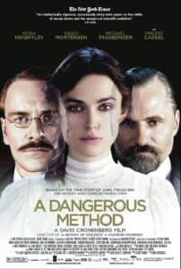 A stylized poster featuring Michael Fassbender (as Carl Jung), Keira Knightley (as Sabina Spielrein), and Viggo Mortensen (as Sigmund Freud). Their faces are dramatically lit, with the central figure of Knightley torn down the middle, visually separating Jung on the left and Freud on the right. The text reads: “Based on the true story of Jung, Freud and the patient who came between them.”