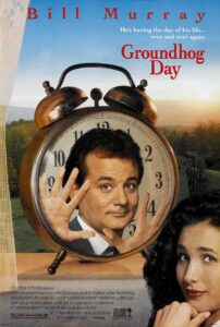 The poster for Groundhog Day features Bill Murray with a puzzled expression, pressing his hands against the inside of a giant alarm clock. Behind him is a serene rural landscape at sunrise. Andie MacDowell appears beside the clock with a knowing smile. The tagline reads, “He’s having the day of his life… over and over again,” hinting at the film’s famous time loop premise.