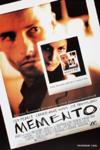 Poster for the film Memento, featuring a recursive image of a Polaroid photograph within a photograph. The main image shows Guy Pearce's character looking off to the side, with a Polaroid of Carrie-Anne Moss layered over his chest. Below the photo is the tagline: “Some memories are best forgotten.”