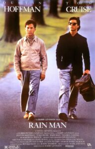Poster for Rain Man featuring Dustin Hoffman and Tom Cruise walking down a tree-lined road. Hoffman wears a beige jacket and looks contemplative, while Cruise, in sunglasses and a black blazer, carries a leather bag. The image captures the film’s journey motif and emotional tone of connection and discovery.