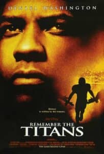 Poster for Remember the Titans featuring a close-up of Denzel Washington’s face in warm golden tones, expressing seriousness and resolve. Below, the silhouette of a football player runs forward, arms outstretched. The tagline reads, “History is written by the winners.” The film’s title appears boldly beneath: Remember the Titans. A small Walt Disney logo sits above the title, and the release date is noted as “THE GAME BEGINS 9.29.00.”