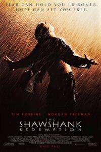 Poster for The Shawshank Redemption showing a man (Andy Dufresne) standing in the pouring rain, arms stretched wide and face turned upward in a moment of emotional release and liberation. Warm, dramatic lighting cuts through the storm. Above him is the tagline: “Fear can hold you prisoner. Hope can set you free.” The title and cast names (Tim Robbins and Morgan Freeman) appear at the bottom.