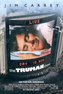 Poster for The Truman Show showing a massive curved digital billboard on a skyscraper with a close-up of Jim Carrey’s character, Truman, smiling in his sleep. Above him, the word “LIVE” glows in red, and below, the day count reads “DAY 10,909.” A huge crowd fills the city square beneath, suggesting that Truman’s life is being broadcast 24/7. The tagline reads: “On the air. Unaware.”